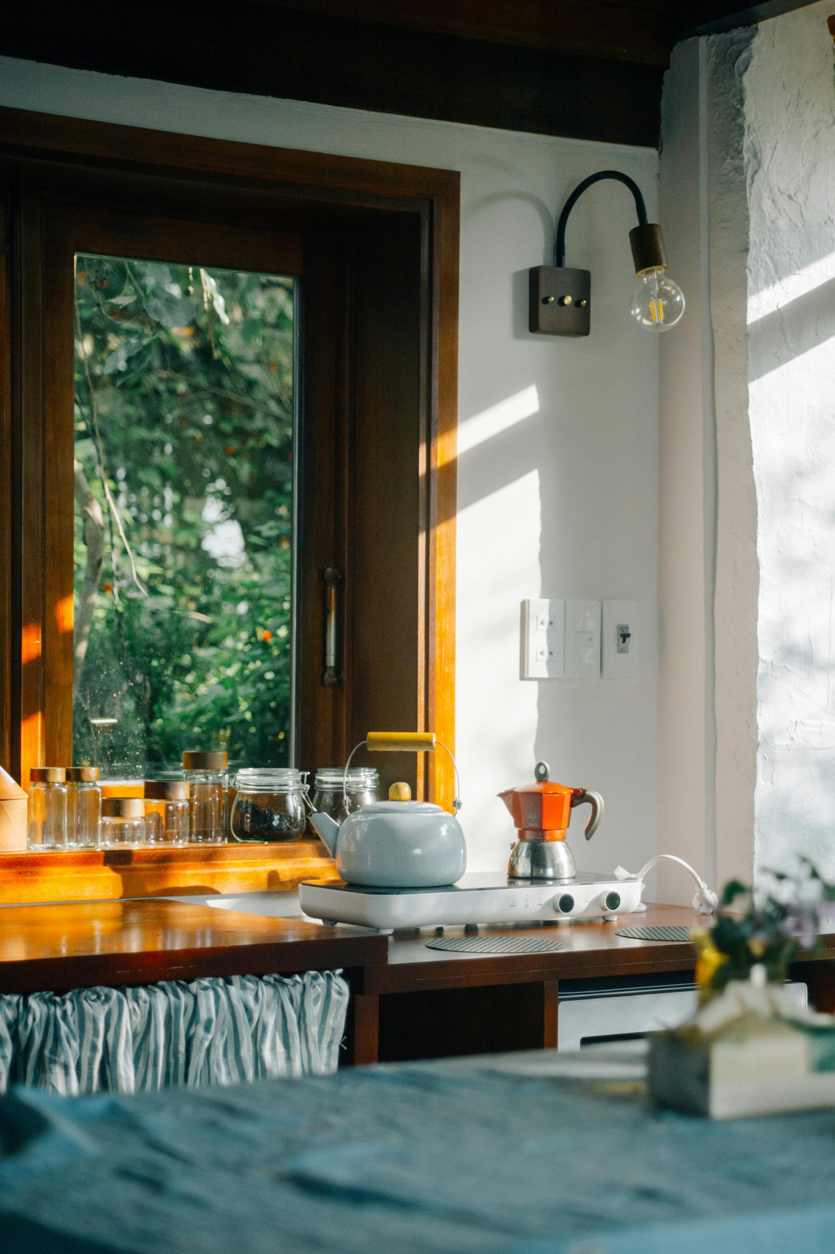 A serene kitchen corner with natural sunlight and a view of lush greenery outside.