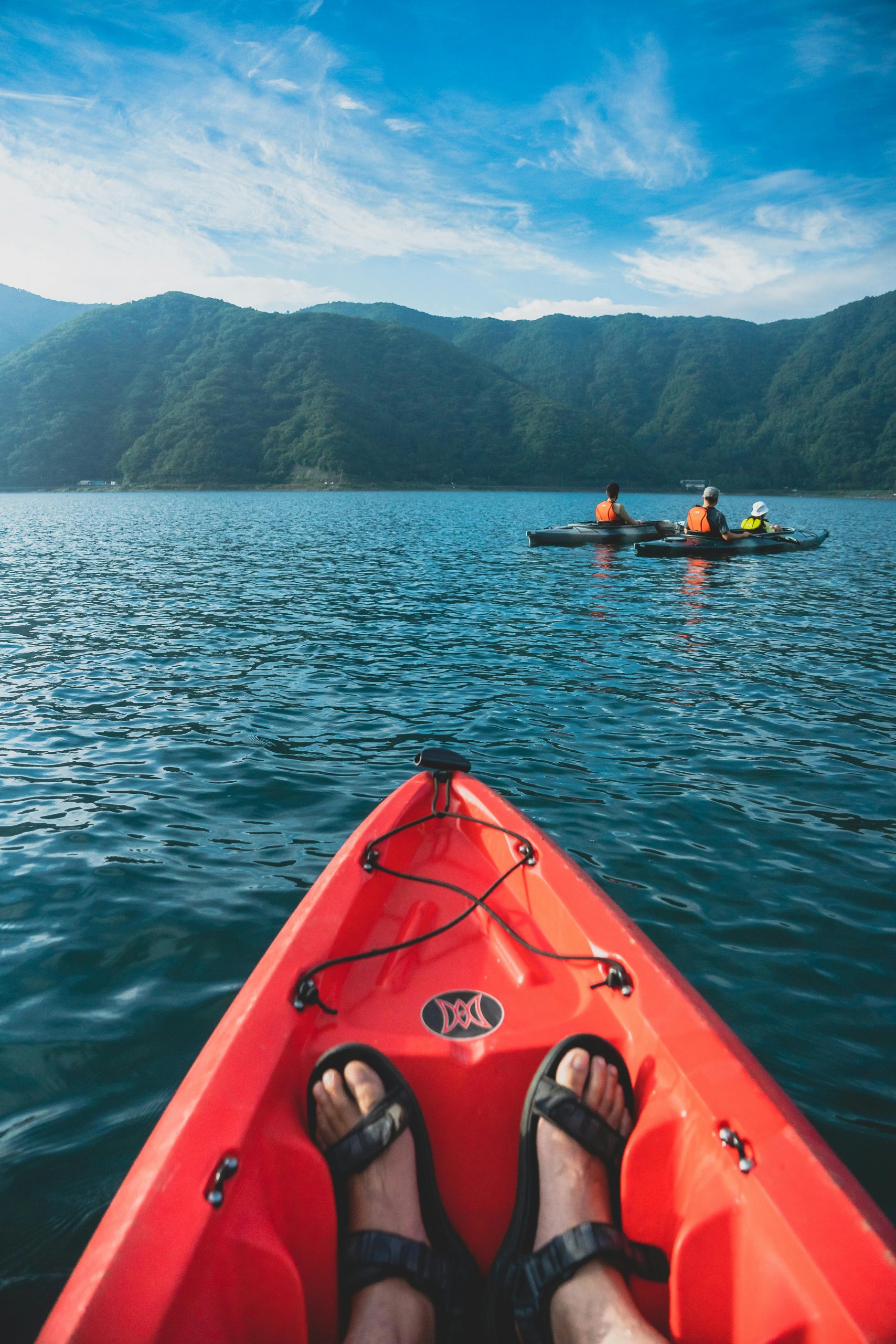 Enjoy the serene experience of kayaking on a beautiful lake surrounded by lush mountains in Japan.